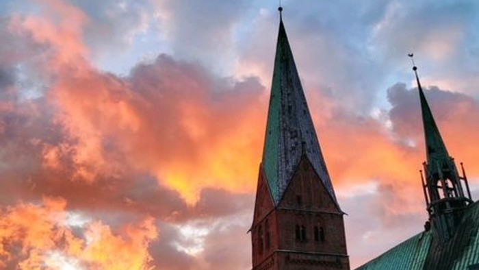 Ein Kirchengebäude mit zwei hohen Türmen bei Sonnenuntergang