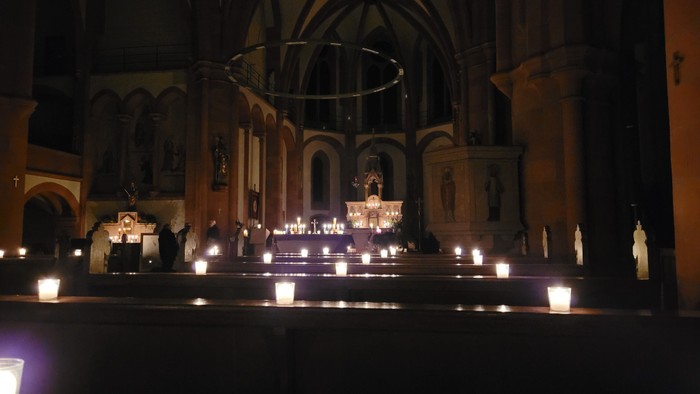 Kircheninneres mit brennenden Kerzen und religiösen Statuen.