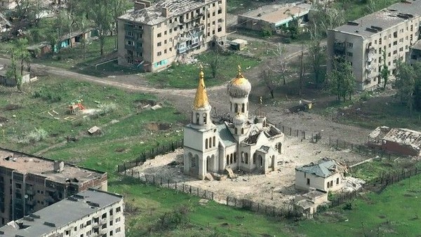 Luftaufnahme einer orthodoxen Kirche mit goldenen Kuppeln, umgeben von Wohngeb�uden und gr�nen Feldern.