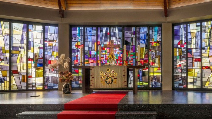 Kircheninneres mit Buntglasfenstern und rotem Teppichgang