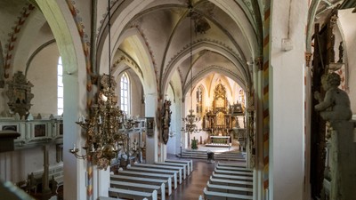 Innenraum einer Kirche mit hohen Bögen, Kirchenbänken und einem Altar am Ende.