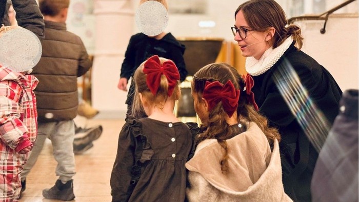 To børn med røde hårbånd taler med en kvinde.