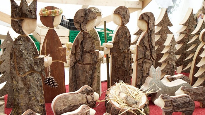 Holzskulpturen einer Krippe mit Maria, Josef und dem Kind Jesus, umgeben von Tieren und Engeln
