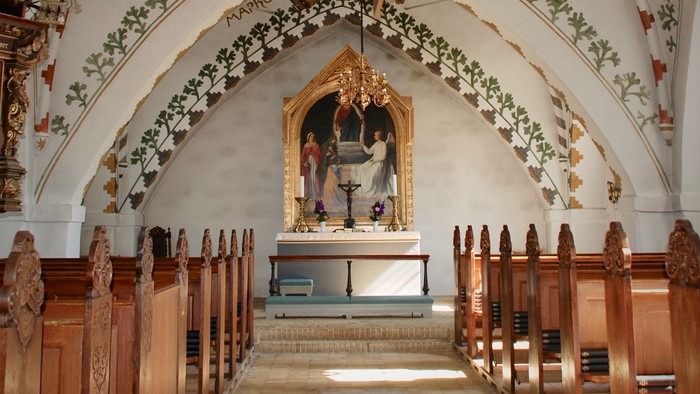 En indre kirkehal med alter og træbænke.