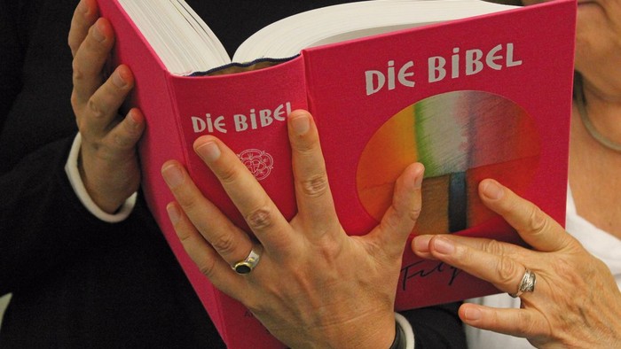 Person hält ein rotes Buch mit der Aufschrift
