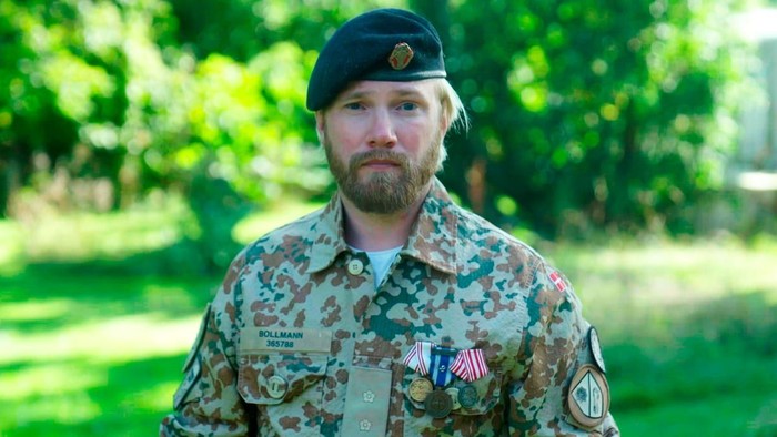 En mand i militæruniform med mønstrede kamouflage og medaljer.