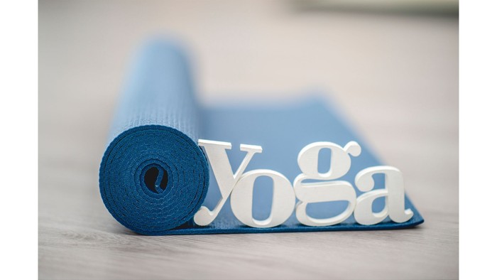 Es ist eine aufgerollte Yogamatte mit dem Schriftzug Yoga zu sehen