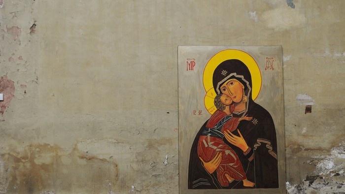 Religious icon of a woman holding a child on a worn wall