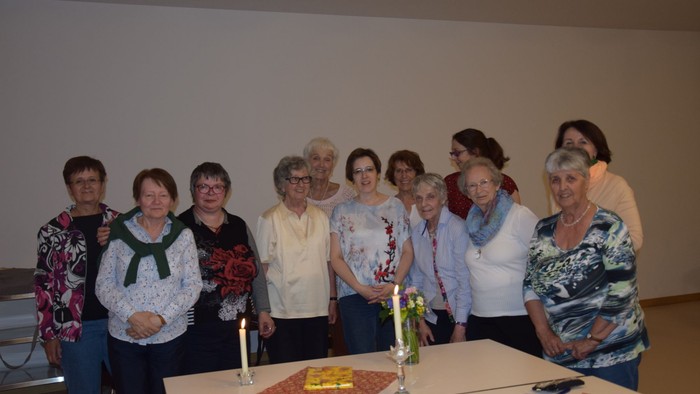 Eine Gruppe von Frauen steht um einen Tisch und lächelt.