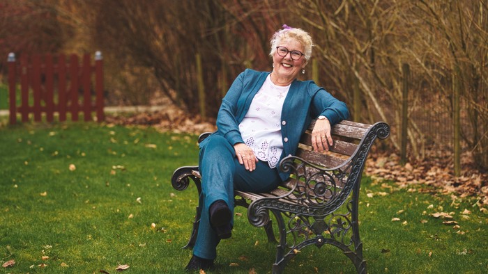 En glad kvinde sidder på en benk i en park