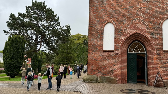 En gruppe af mennesker går ud af en rød murstenskirke.