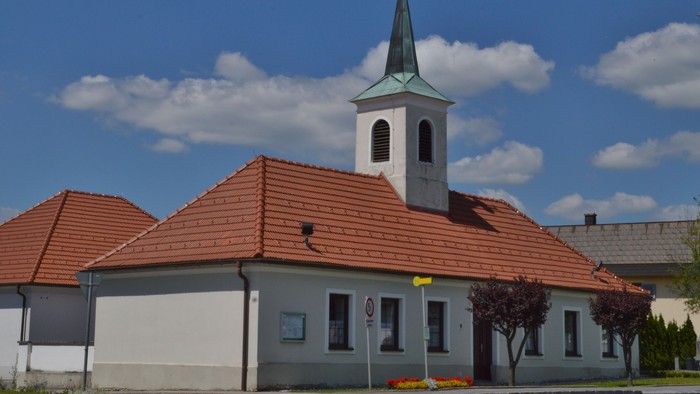 Kirche mit hohem Turm und rotem Dach unter blauem Himmel