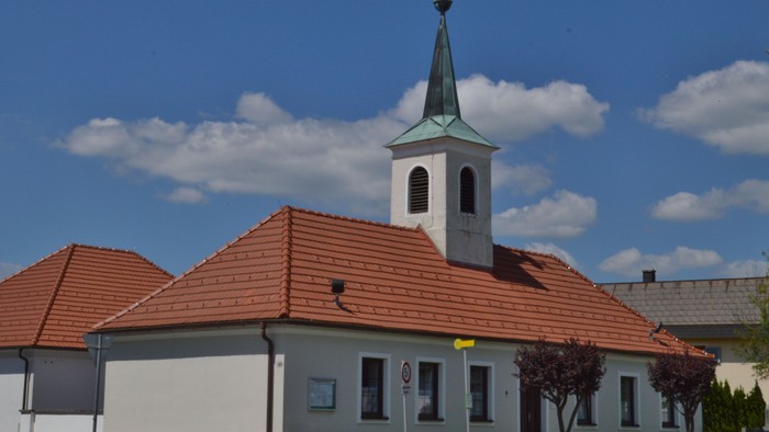 Kirche mit hohem Turm und rotem Dach unter blauem Himmel
