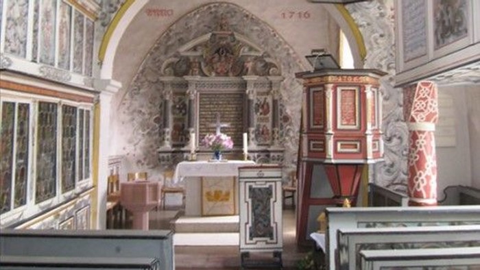 Die Kirche hat einen schönen Altar und hohe Decken.