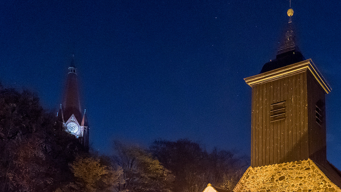 Zwei Türme, einer rot und einer braun, stehen vor einem dunkelblauen Nachthimmel.