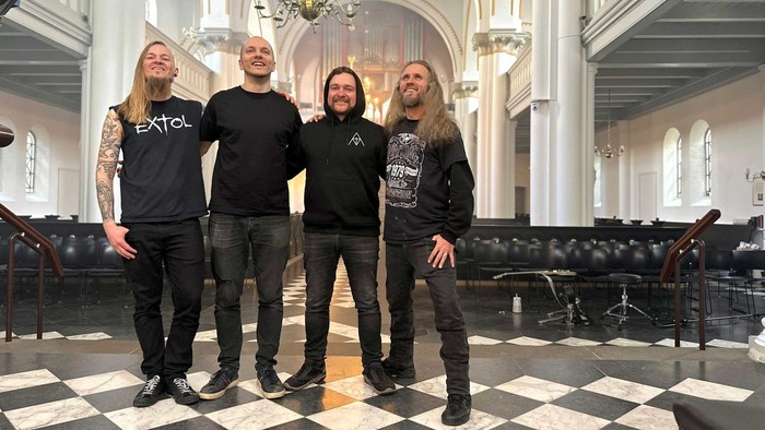 Fire mænd står sammen i en kirke.