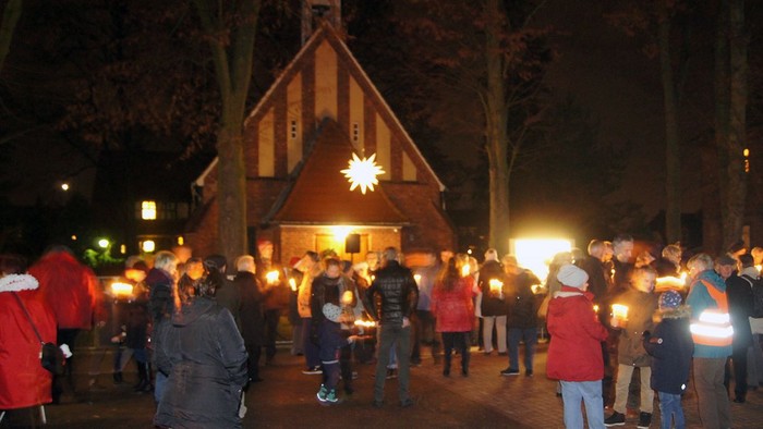 Menschen mit Kerzen singen vor beleuchteter Kirche