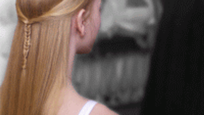 En kvinde med lang blond hår, der holder en mobiltelefon.