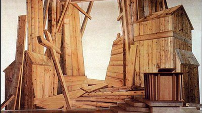 Abstrakte Holzkonstruktion, die einem chaotischen, unvollendeten Architekturmodell oder einer Skulptur ähnelt.