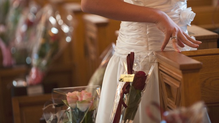 En brud i hvid kjole står ved et bord med blomster.