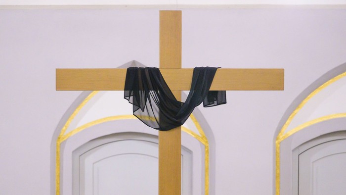 Kreuz mit schwarzem Tuch zwischen zwei weißen Bögen behangen