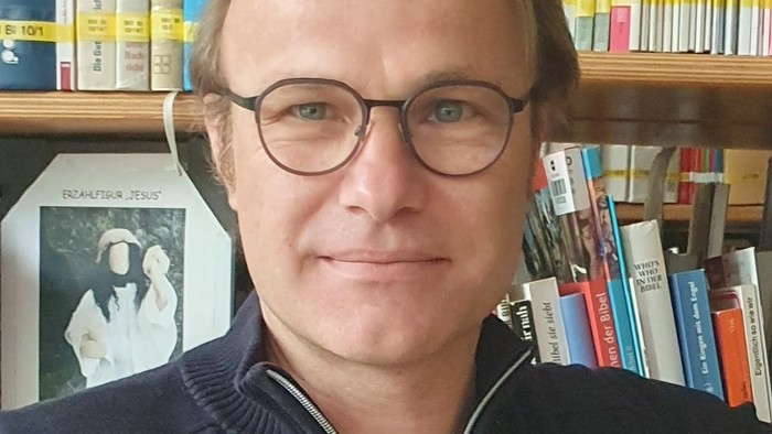 Mann mit Brille vor Bücherregal