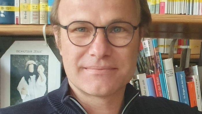 Mann mit Brille vor Bücherregal