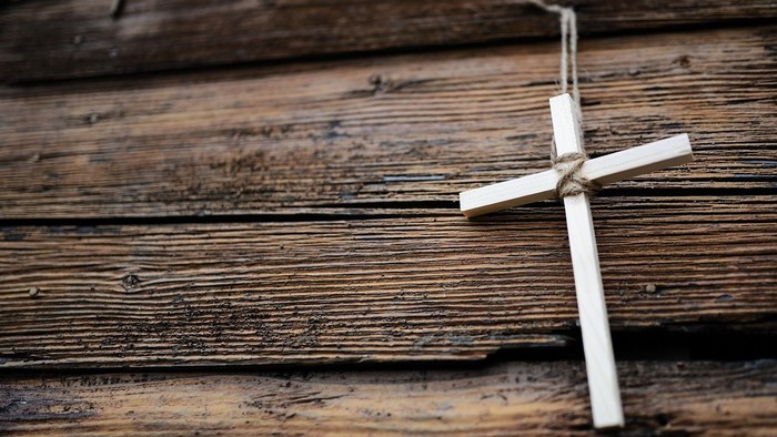 Ein kleines Holzkreuz liegt auf verwitterten Holzbohlen.