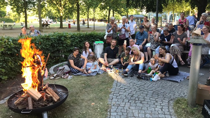 En gruppe af mennesker sidder omkring en bålplads i en park