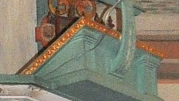 Ein grüner Metallkorb mit verzierten Eisengriffen an einer Wand