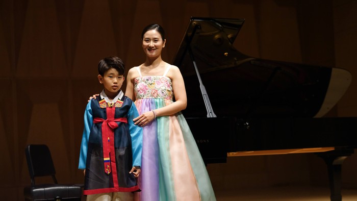 To børn i kostumer poser ved siden af et flygel