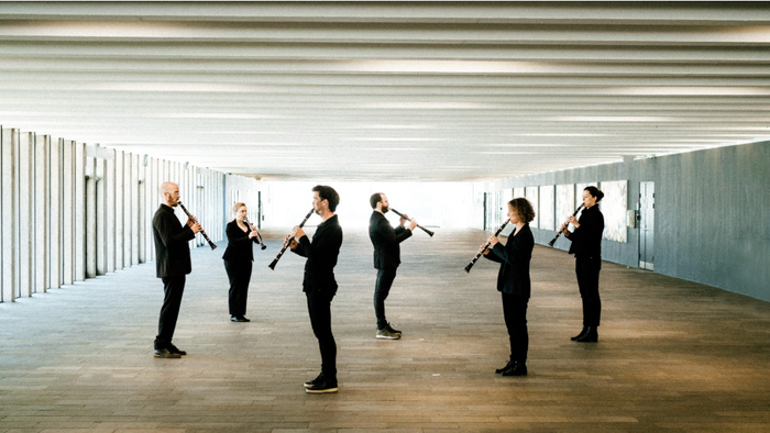 En gruppe musikere, der spiller fløjter i en moderne, rummelig indendørs gang.