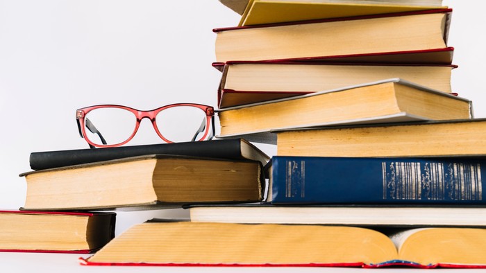 Eine Brille liegt auf einem Stapel Bücher.