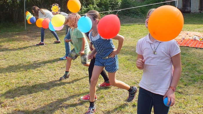 Kinder spielen im Garten mit bunten Ballons
