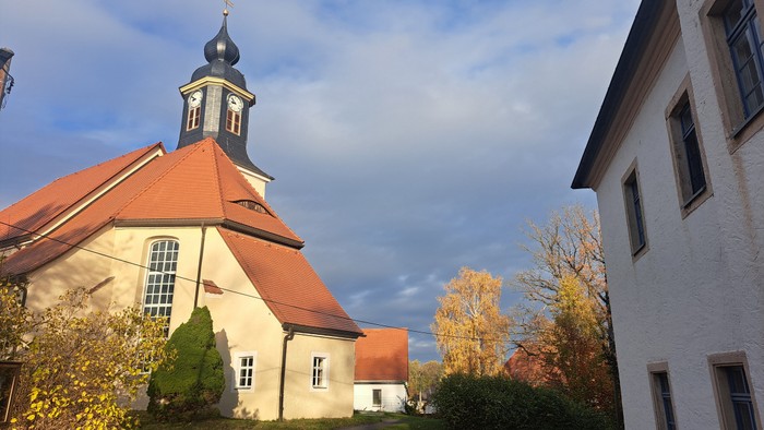 Kirchengrundstück mit weißem Gebäude und rotem Dach unter blauem Himmel
