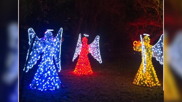 Drei Engel aus Lichtern in Blau, Rot und Gelb vor dunklem Hintergrund