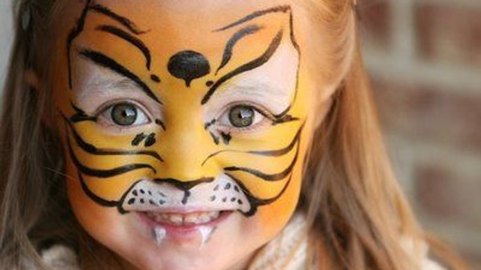 Et barn med tigresmalet på ansigtet.