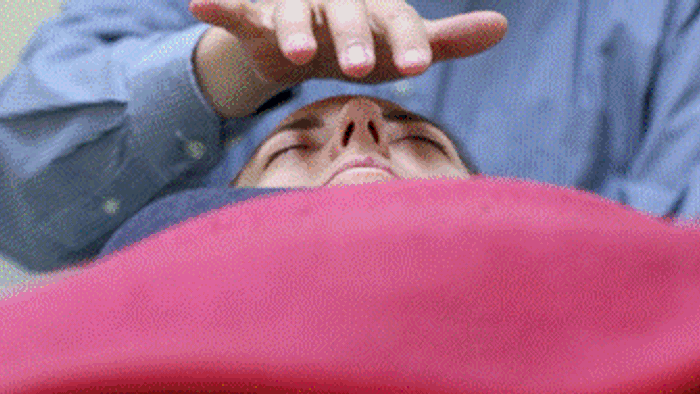 En person ligger på ryggen og holder håndene oppe over ansigtet.