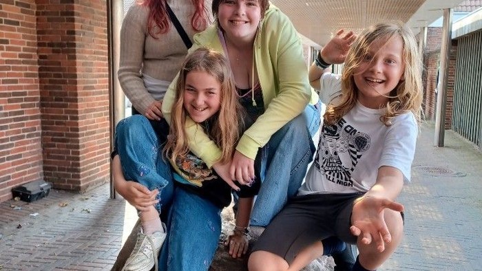 Fire piger sidder på en stor sten under en overbygning