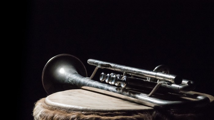 Ein silbernes Blechblasinstrument liegt auf einem Fell.