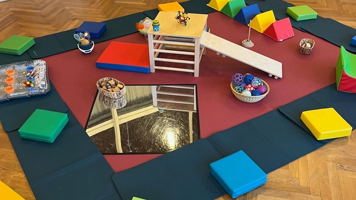 Bunter Spielplatz mit Rutsche und Kissen auf Holzboden