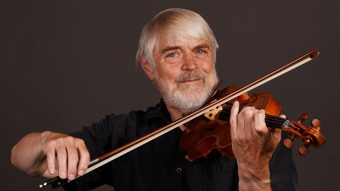 Erfaren mand spiller violin med et fokuseret udtryk.