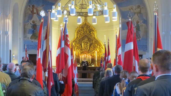 En kirkeindgang med mange flag og en stor gylden altertavle