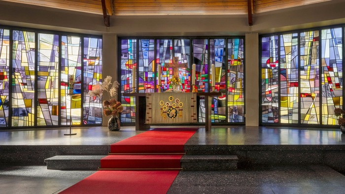 Kircheninneres mit Buntglasfenstern und rotem Teppichgang