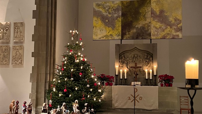 In der Kirche steht ein geschmückter Weihnachtsbaum vor dem Altar.