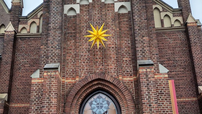 Backsteinkirche mit hohen Türmen und einer großen Holztür.