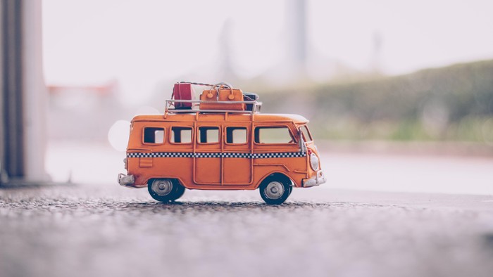 Ein orangefarbenes Miniatur-Camperauto auf einer grauen Oberfläche