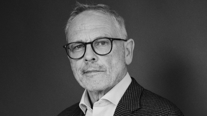 Mand i jakkesæt og briller poser til sort-hvidt foto.