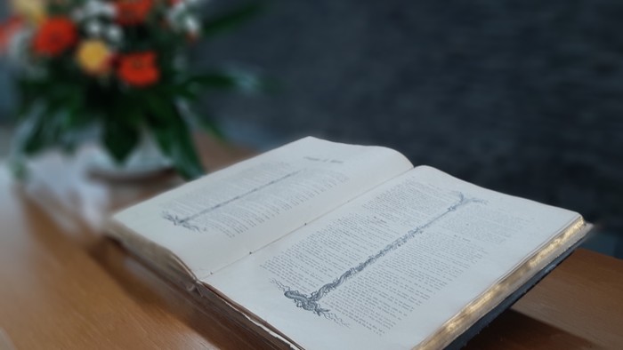 Offenes Buch auf Holzoberfläche neben Blumenstrauß