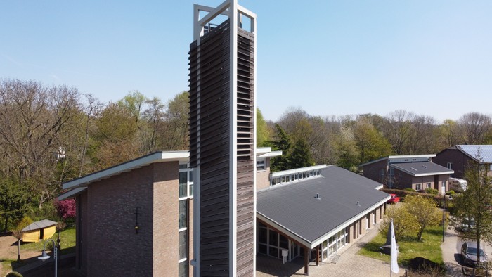 Modernes Gebäude mit hohem Turm und umliegender Grünfläche